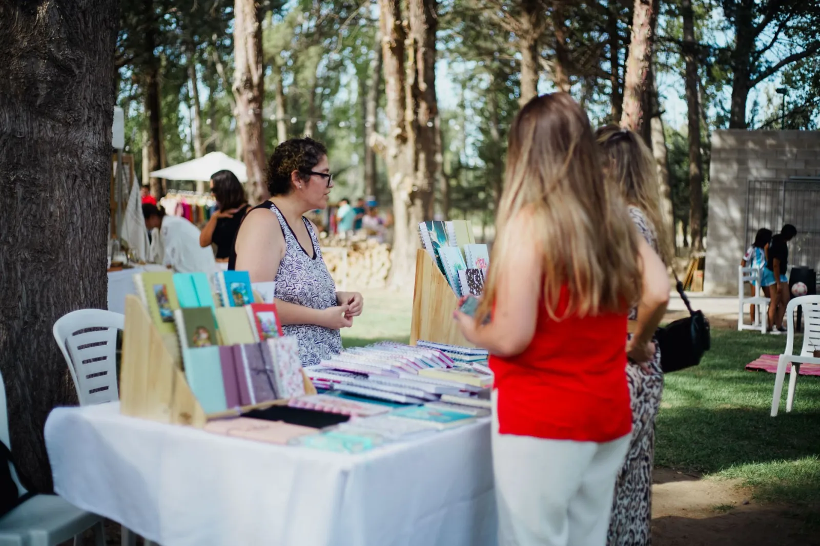 A vibrant outdoor market scene showing notebooks on display with people browsing.