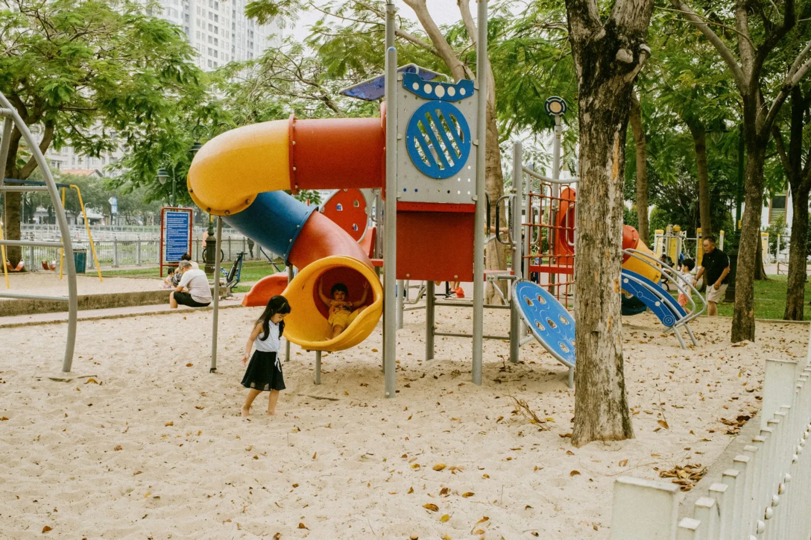 Kids enjoying colorful slides and play structures in an outdoor park playground.