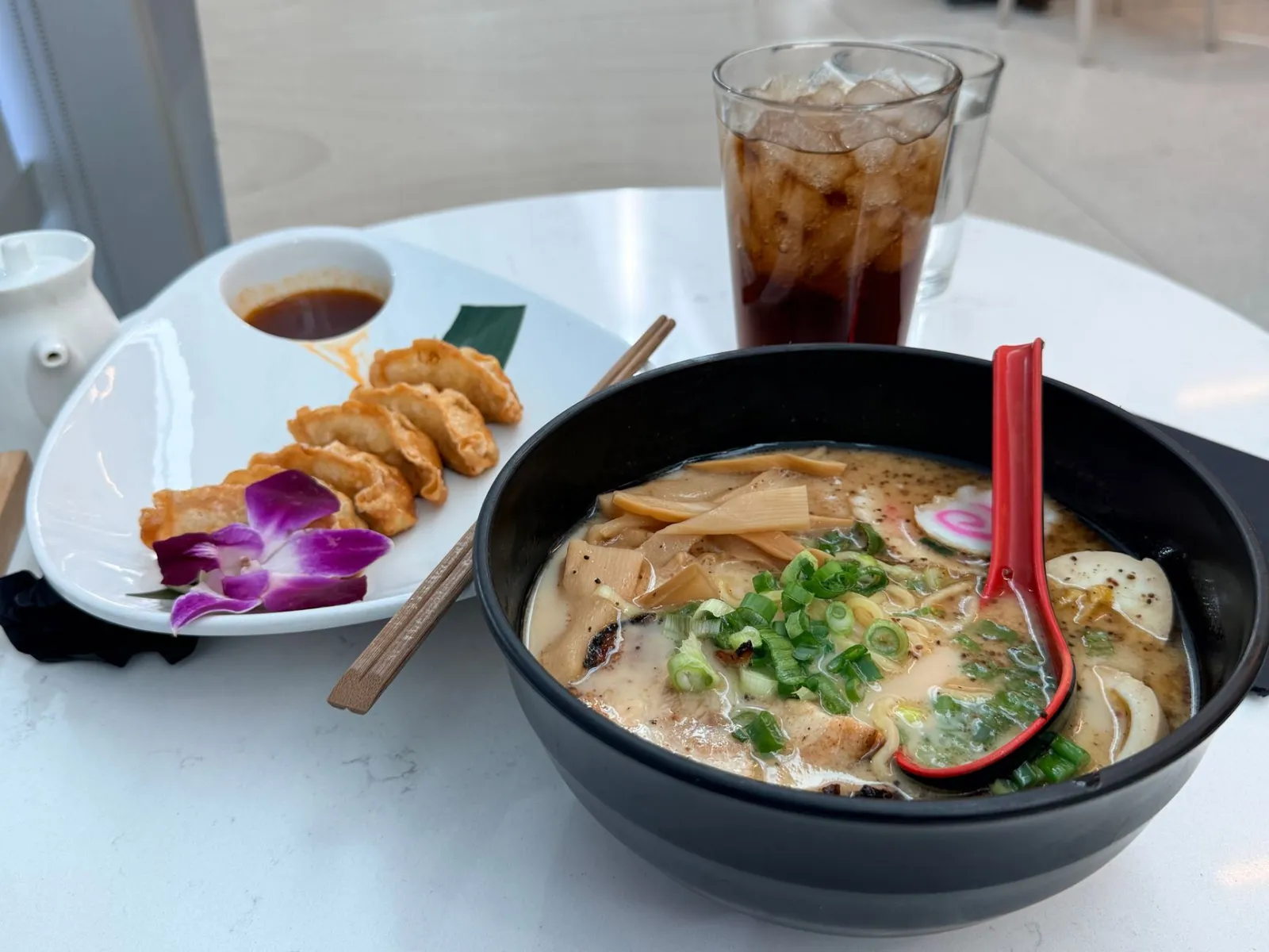 A mouthwatering display of ramen and gyoza with iced drink, showcasing authentic Japanese cuisine.