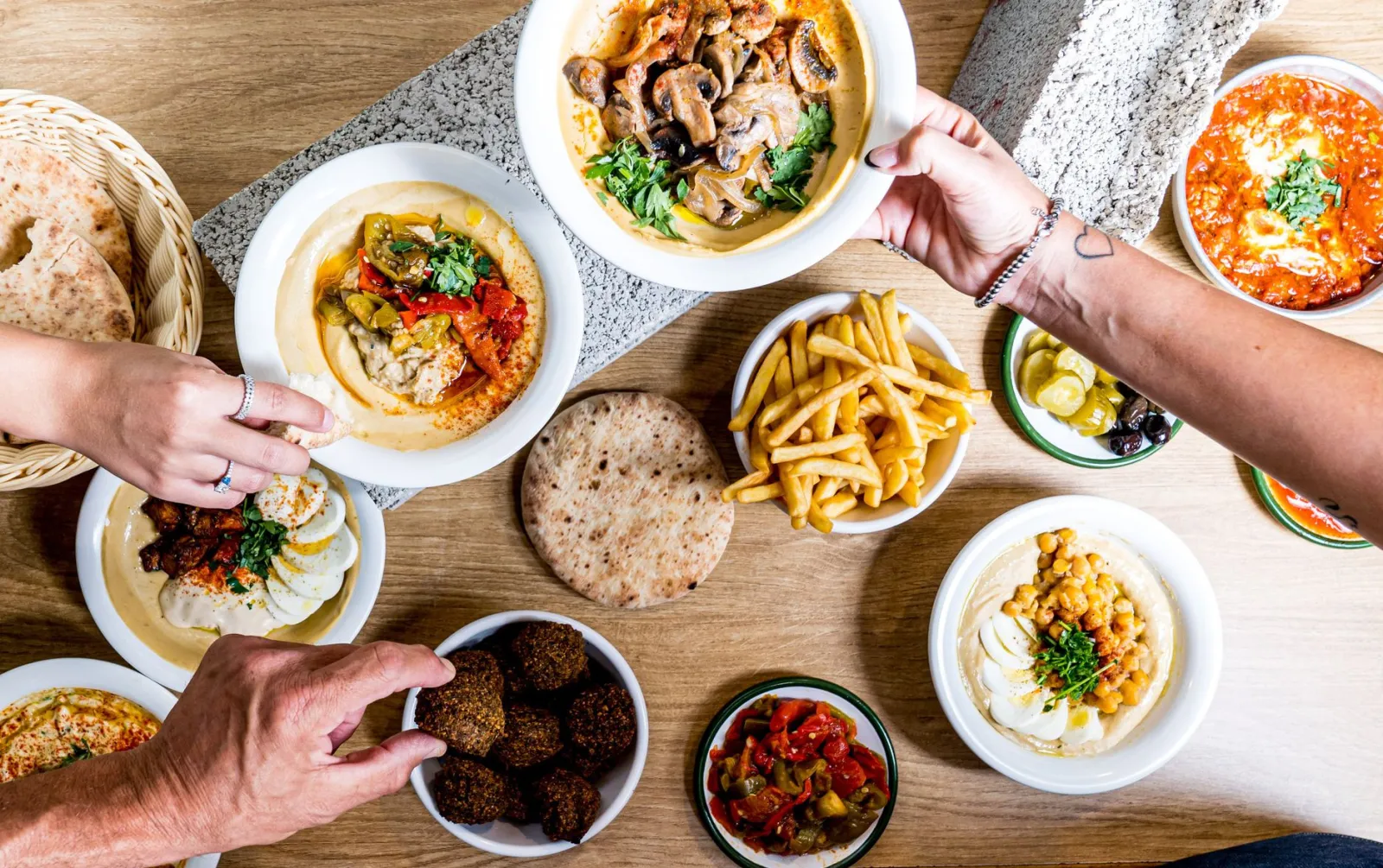 A vibrant spread of Middle Eastern cuisine featuring hummus, falafel, and pita bread on a wooden table.